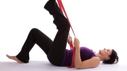 Training with the Theraband - sports for home / a woman trains her leg with Therabands