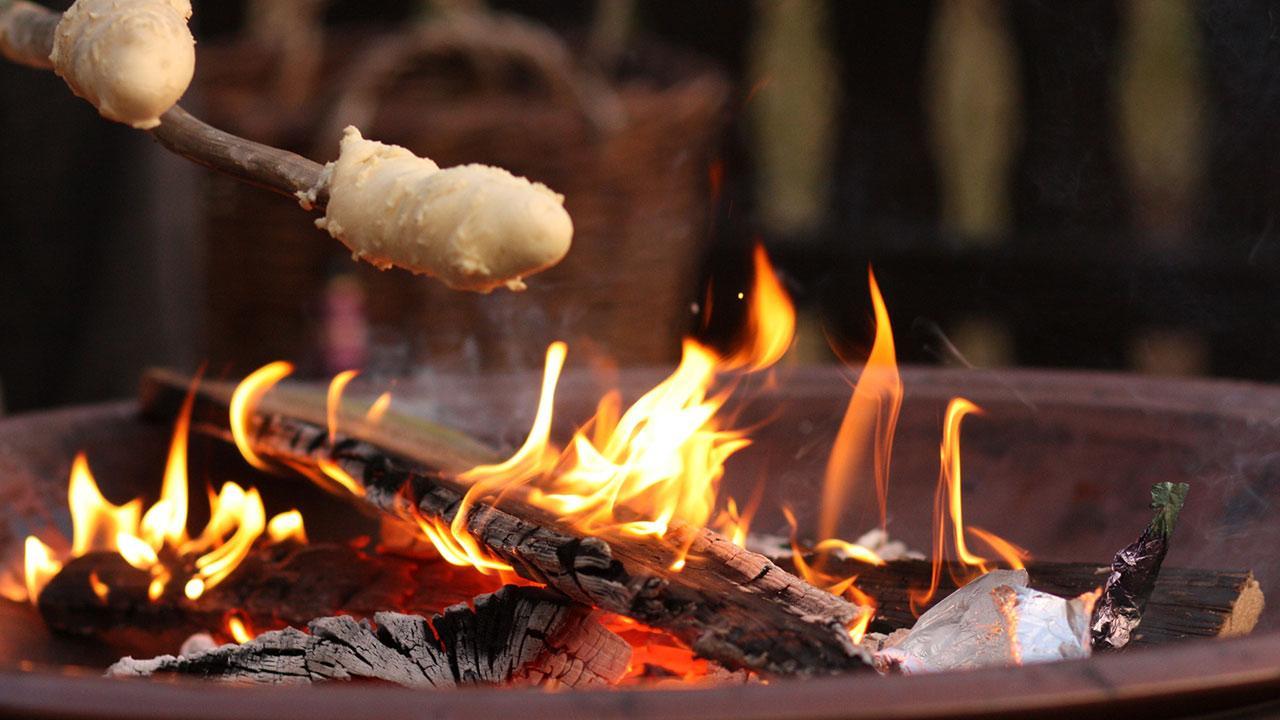 Stick bread at the campfire with children / close-up of a stick bread over the fire