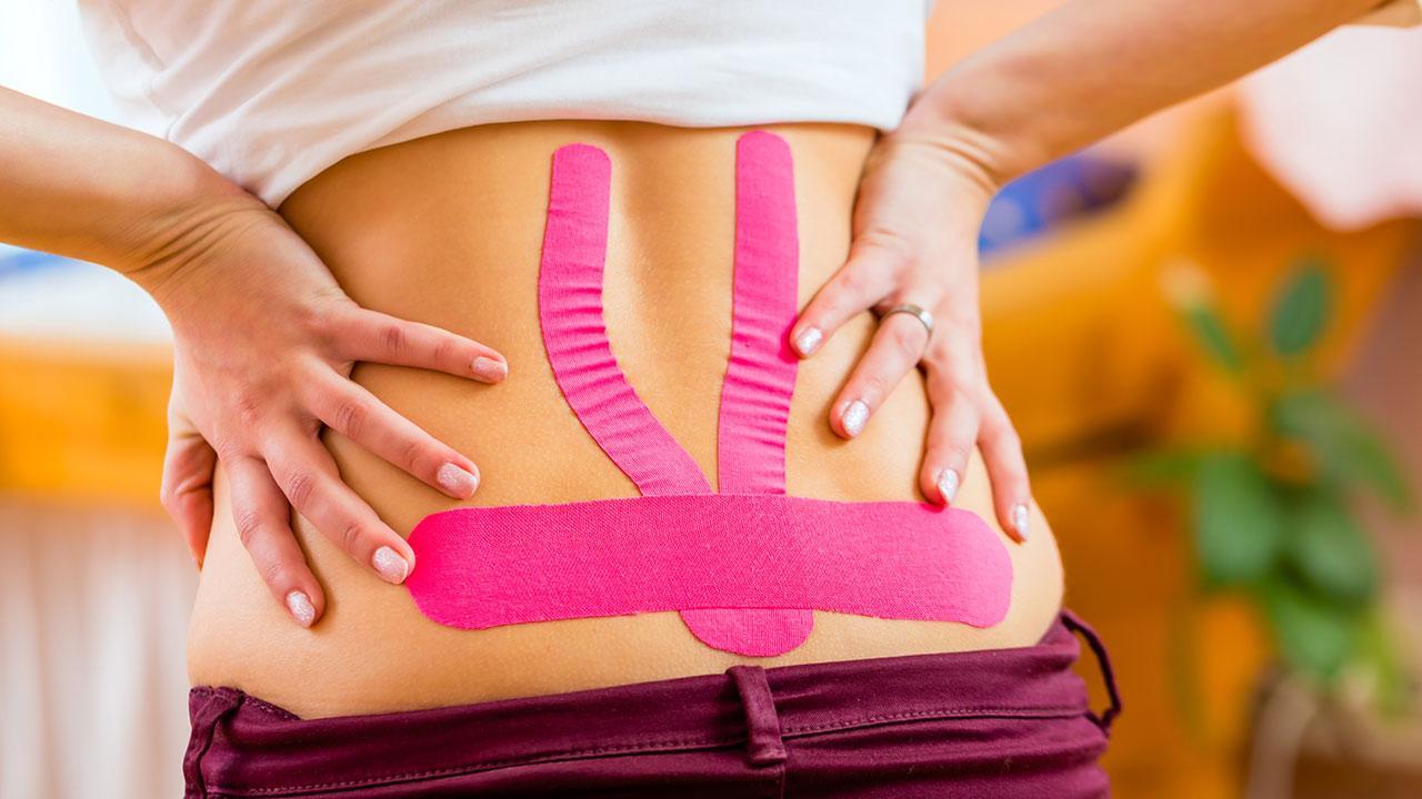 Taping - Does taping help against back pain? / a woman has a taped back