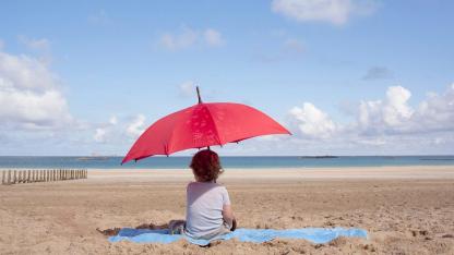 The right sun protection for my child / a small child sitting under a parasol