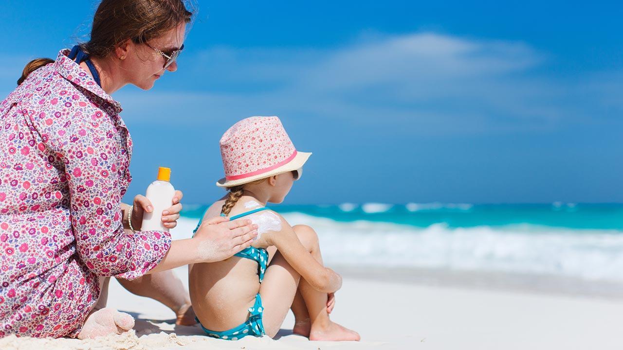 The right sun protection for my child / a woman greases her daughter's back